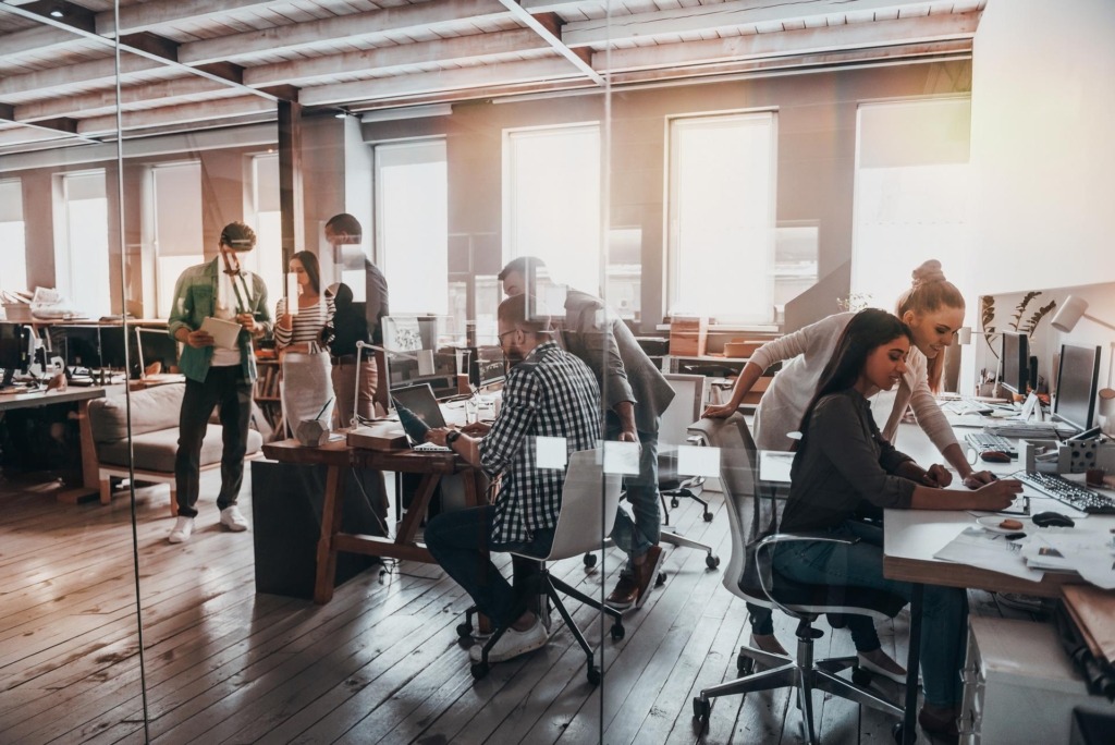 Office setting with people at desks and collaborating with each other
